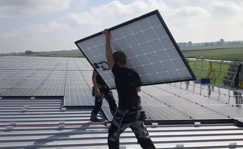 Monteur die een zonnepaneel draagt
