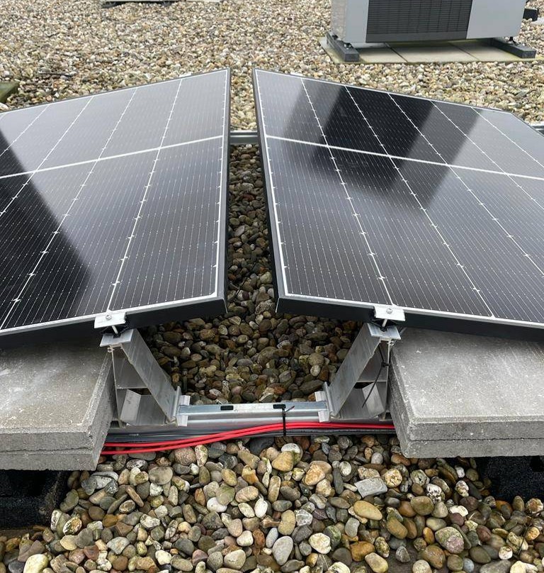 Zonnepanelen op een platte dak in een oost-west opstelling.