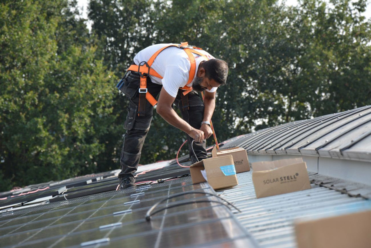 Een zonnepanelen monteur op een schuin dak
