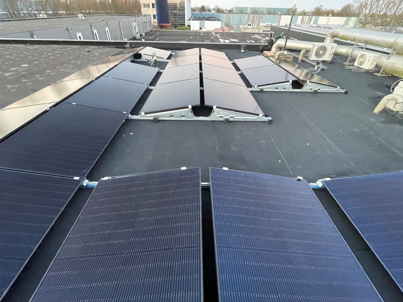 Zonnepanelen op een platte dak in een oost-west opstelling.